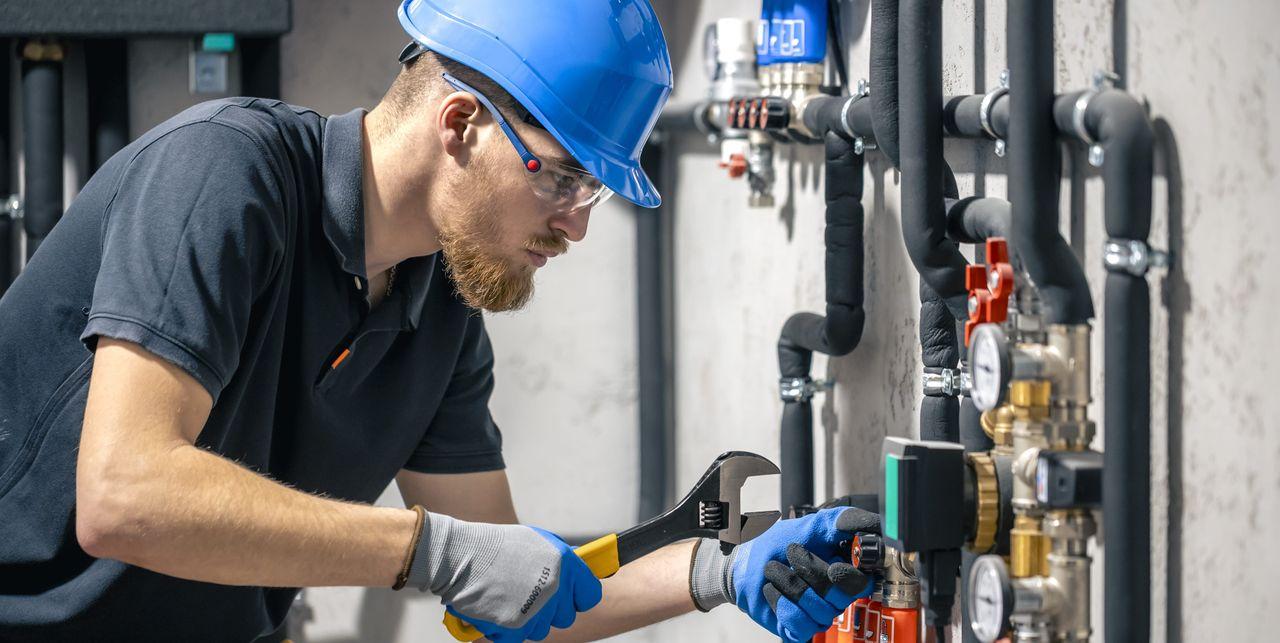 SHK-Fachhandwerker prüft eine moderne Heizungsanlage mit sauber verlegten Rohrleitungen